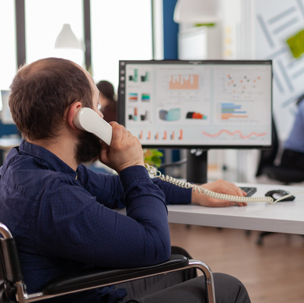 busy-disabled-team-leader-answering-phone-talking-with-partner-typing-computer-explaning-project-idea-checking-financial-data